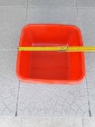 Kwadratowy pojemnik plastikowy czerwony z bocznymi uchwytami, o boku ok. 25 cm, 
